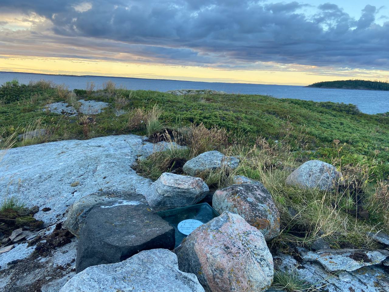 The glass archive tablet nestled among rocks on a small White Sea island at sunset
