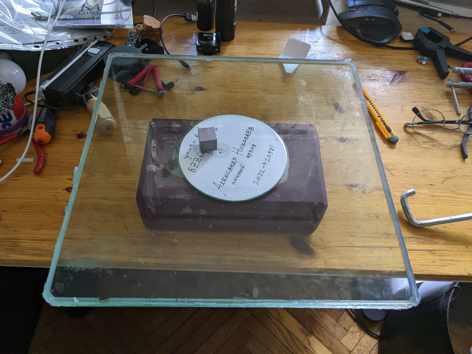 An archival disc resting inside the glass layers of a homemade tablet on a workbench
